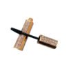 Cross placed empty mascara packaging with crocodile texture leather wrap, applicator stem pulled out
