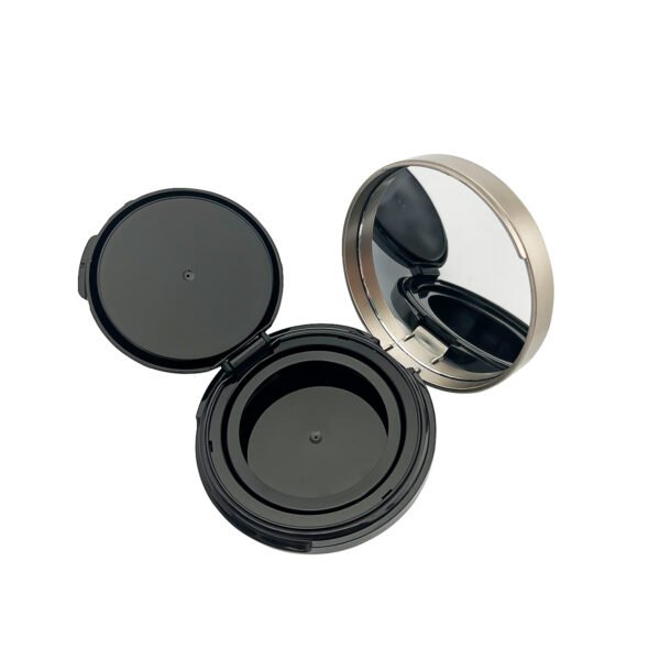 Round empty powder compact fully opened, showing built-in mirror, glossy black powder tray and separate inner cover